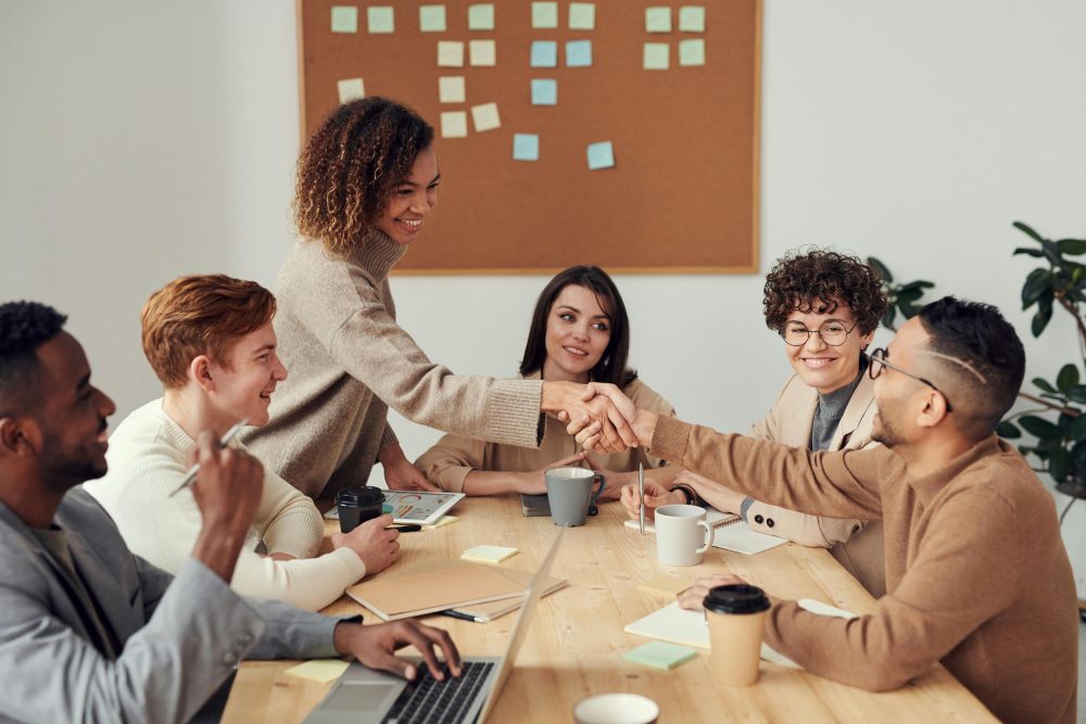 Gruppe von Menschen arbeitet an einem Tisch mit Handschlag
