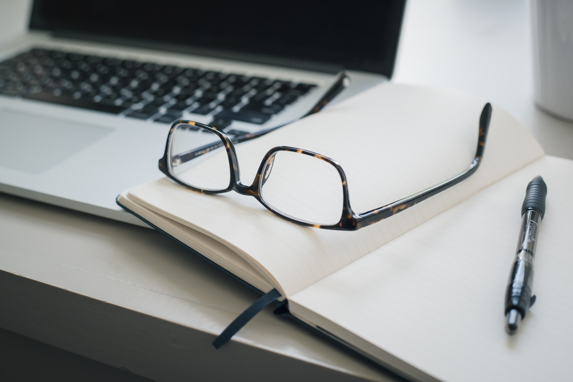 A symbolic image for transcreation and localization services German, English, and French in Dresden: a pair of glasses and a pen lie on an open notebook next to a laptop.