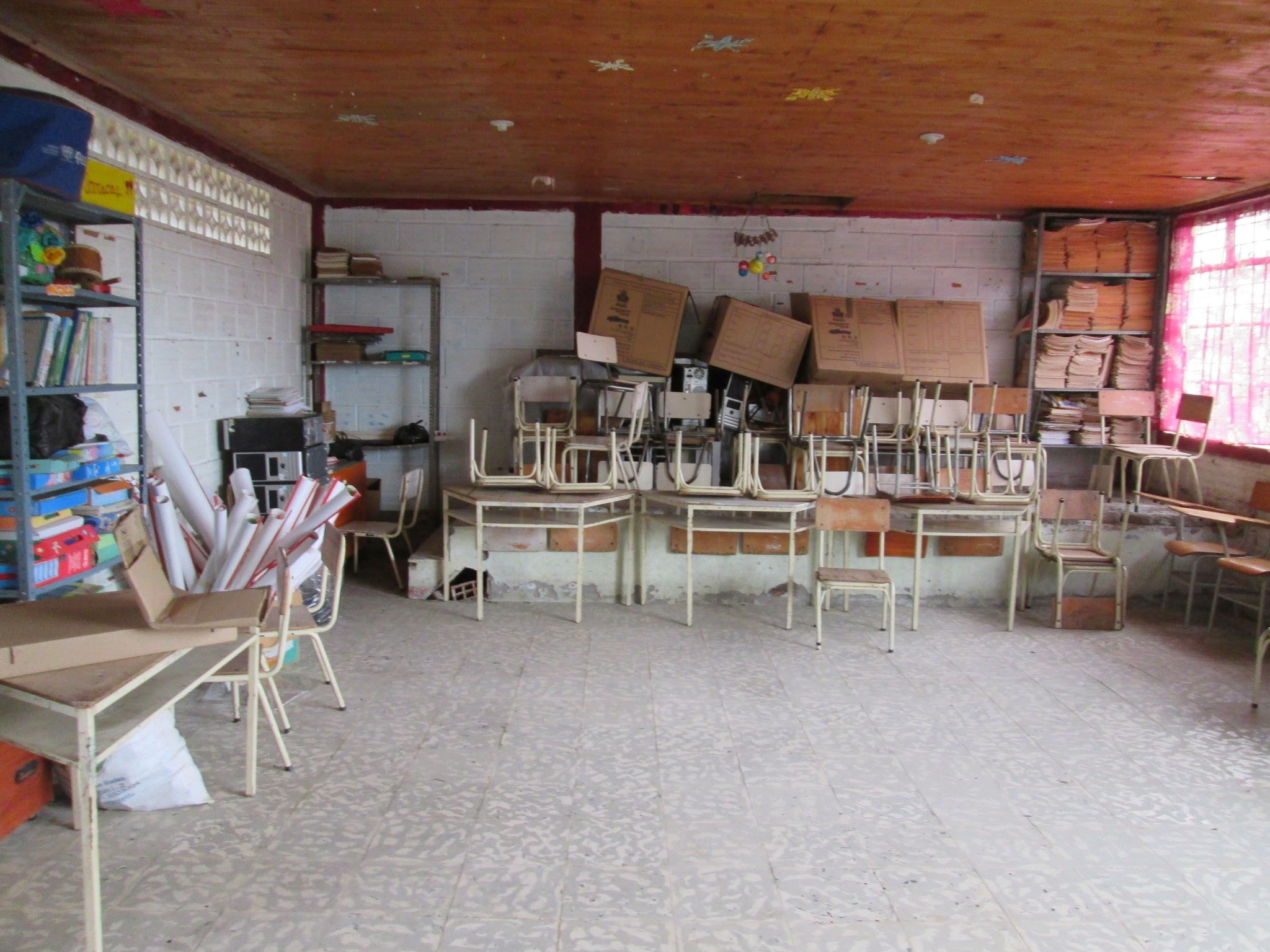 Estado previo del aula de la escuela abandonada y convertida en cuarto de almacenamiento de cosas viejas, dañadas y olvidadas.