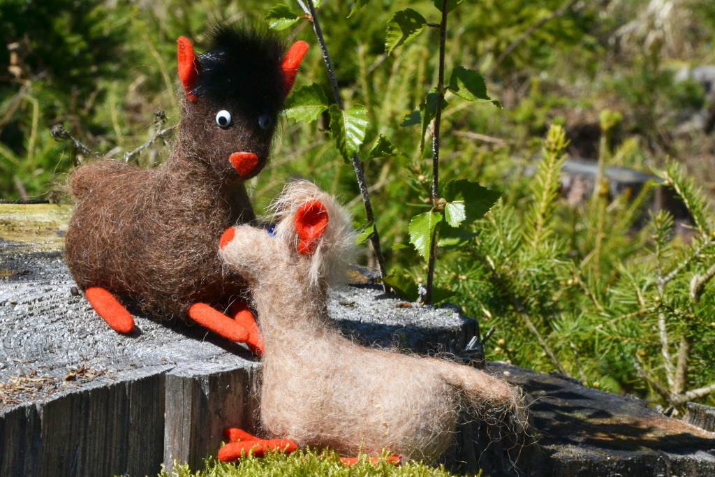 Dunkelbraunes und hellbraunes Filzalpaka auf einem Holzstamm