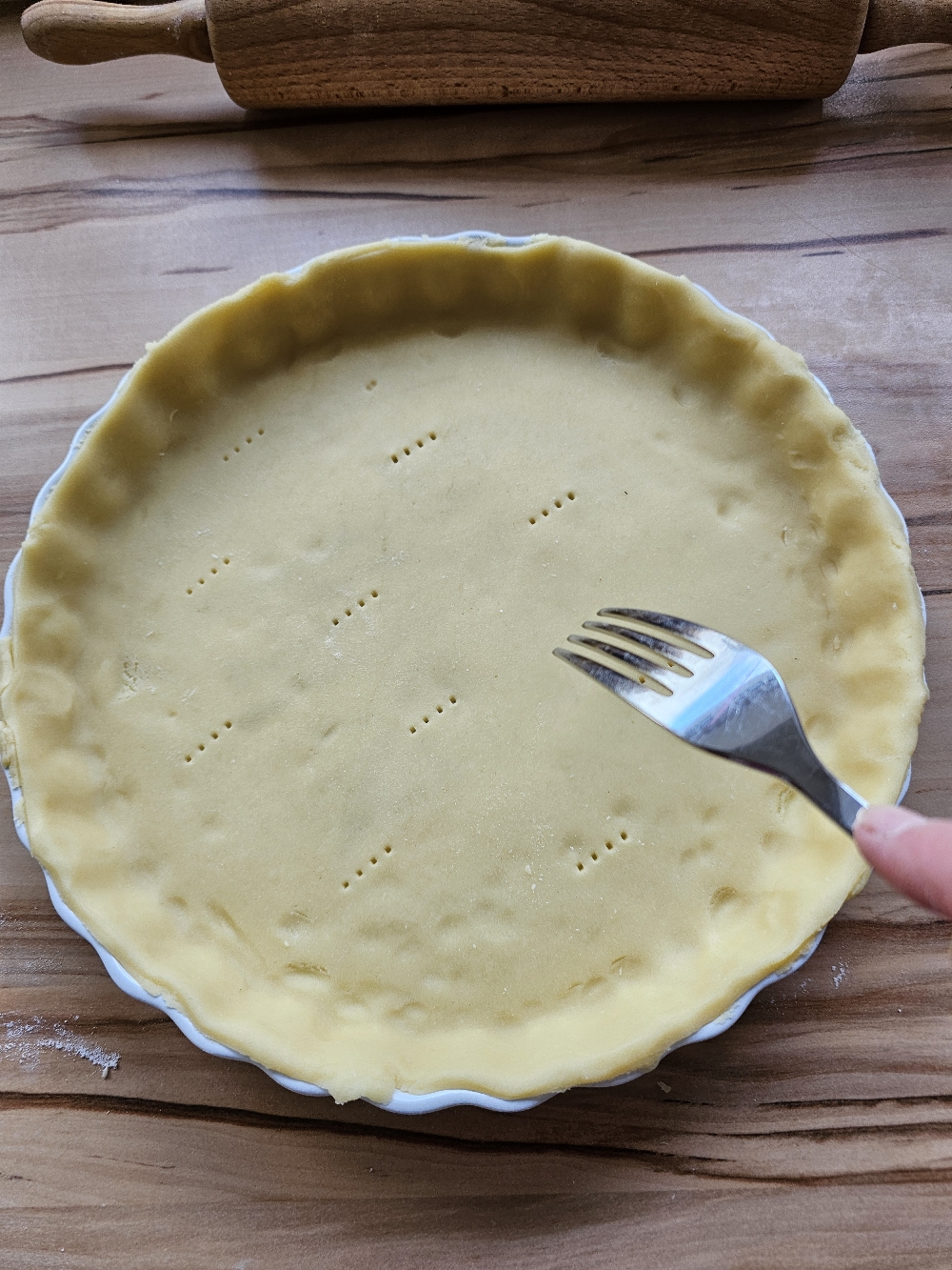 Quiche-Teig mit der Gabel einstechen für eine Quiche Lorraine