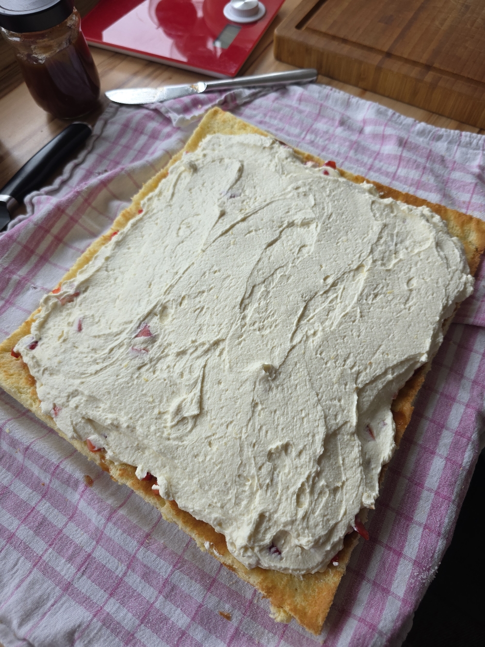 Creme auf dem Biskuitboden für Erdbeer-Biskuitrolle