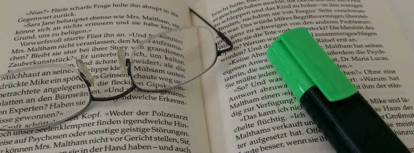 aufgeklapptes Buch mit einer Brille und Stift