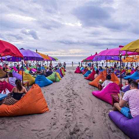 Kleurrijk strandtafereel met zitzakken en parasols op Seminyak Beach.