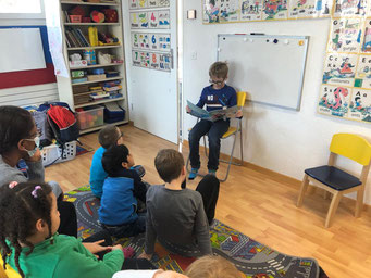 Child reading aloud to classmates to build confidence and speaking skills.
