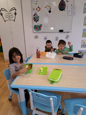 Children enjoying lunch together before English activities at Custom Kids.