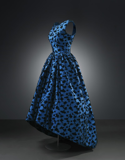 Vestido de noche, con falda asimétrica. 1957. Con un lujoso tejido azul adornado con motivos florales en terciopelo azul.