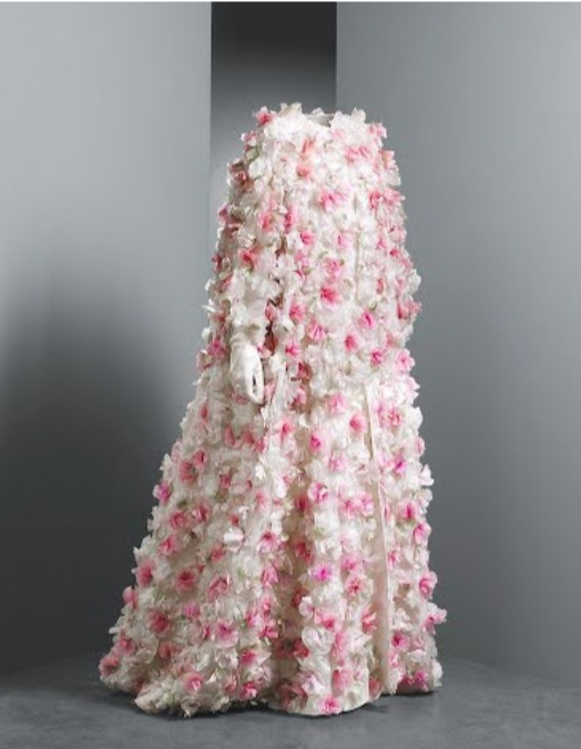 Abrigo de fiesta 1960 Largo, recto y suelto, con manga tres cuartos y escote a la caja. Va guarnecido con una aplicación de flores con pétalos de organza de colores rosa y marfil, y hojas en tafetán de seda verde. Forrado en organza de seda de color ma