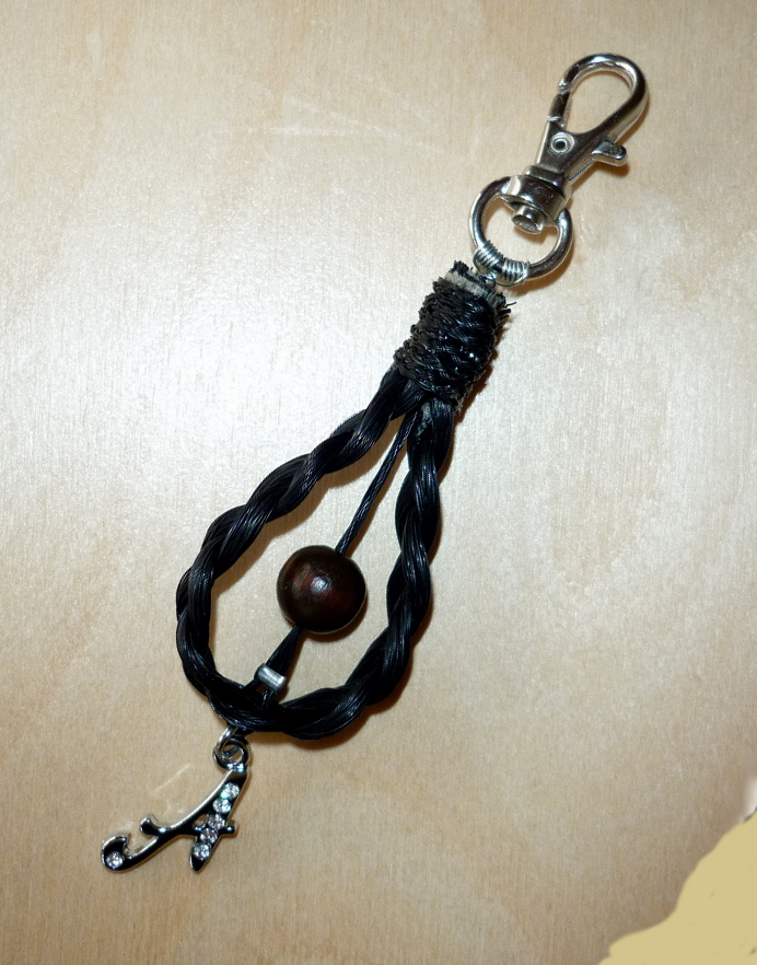 Dreifach (Zopf) geflochtener Schlüsselanhänger mit einem Buchstaben-Anhänger aus silberfarbenem Metall mit Strass-Steinen und einer braunen Holzperle - Preis: 40 Euro