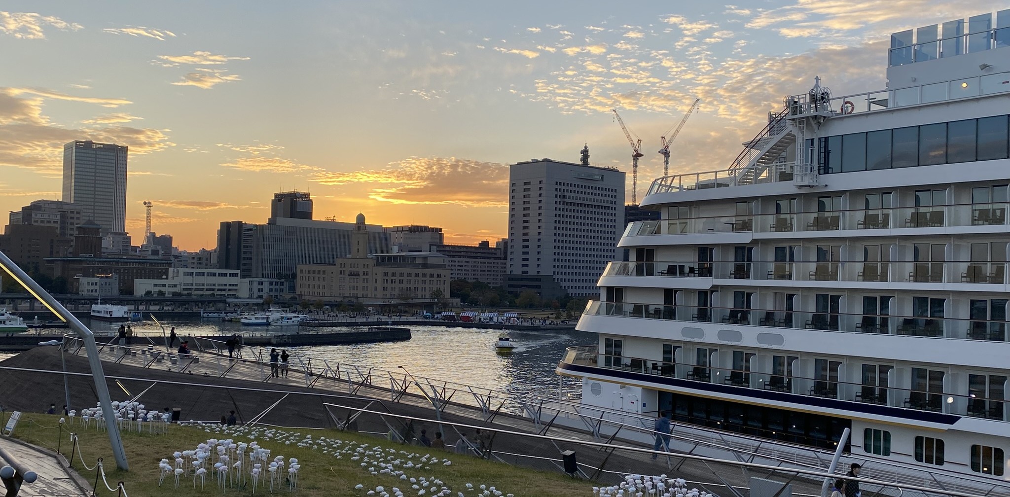 夕映えの横浜大桟橋に停泊する「飛鳥Ⅱ」と、左手に見える「横浜税関」のクラシックな姿（2025年11月24日）。