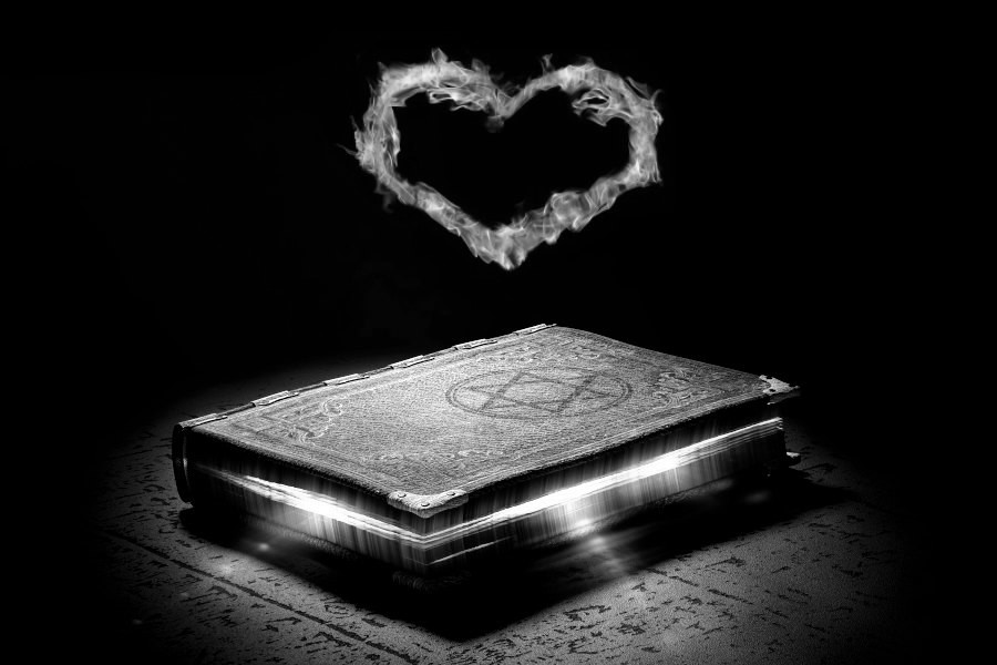 altes magisches buch das von innen leuchtet mit herz aus flammen darüber