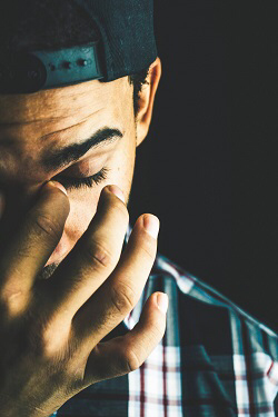 A man rubbing at the inside of his eye. He is clearly stressed.