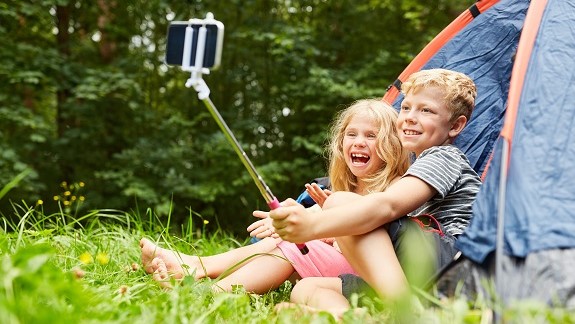 Campingplatz mit Zelt und zwei Kindern, die Selfies machen