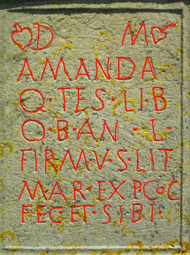 Inschrift: Den Totengöttern. Amanda, Freigelassene des Quintus Tesius. Sie starb im Alter von 50 Jahren. Firmus, Sohn des Litugena, ihr Gatte, hat aus Eigenem der lieben Gattin den Stein errichtet.