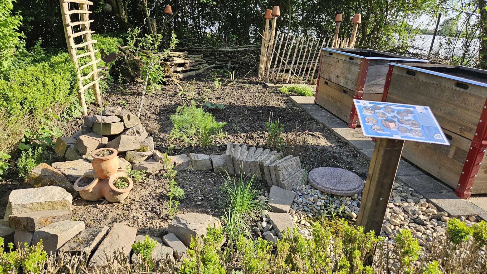 Kräuterbeet mit Trockenmauer, Steinpyramide und angrenzender Wasserstelle: Lebensräume in der Ertragszone. Das Kräuterbeet wurde mit einer Trockenmauer, einem Spaltenbeet aus Gehwegplatten und einer innen hohlen Steinpypramide eingefasst.