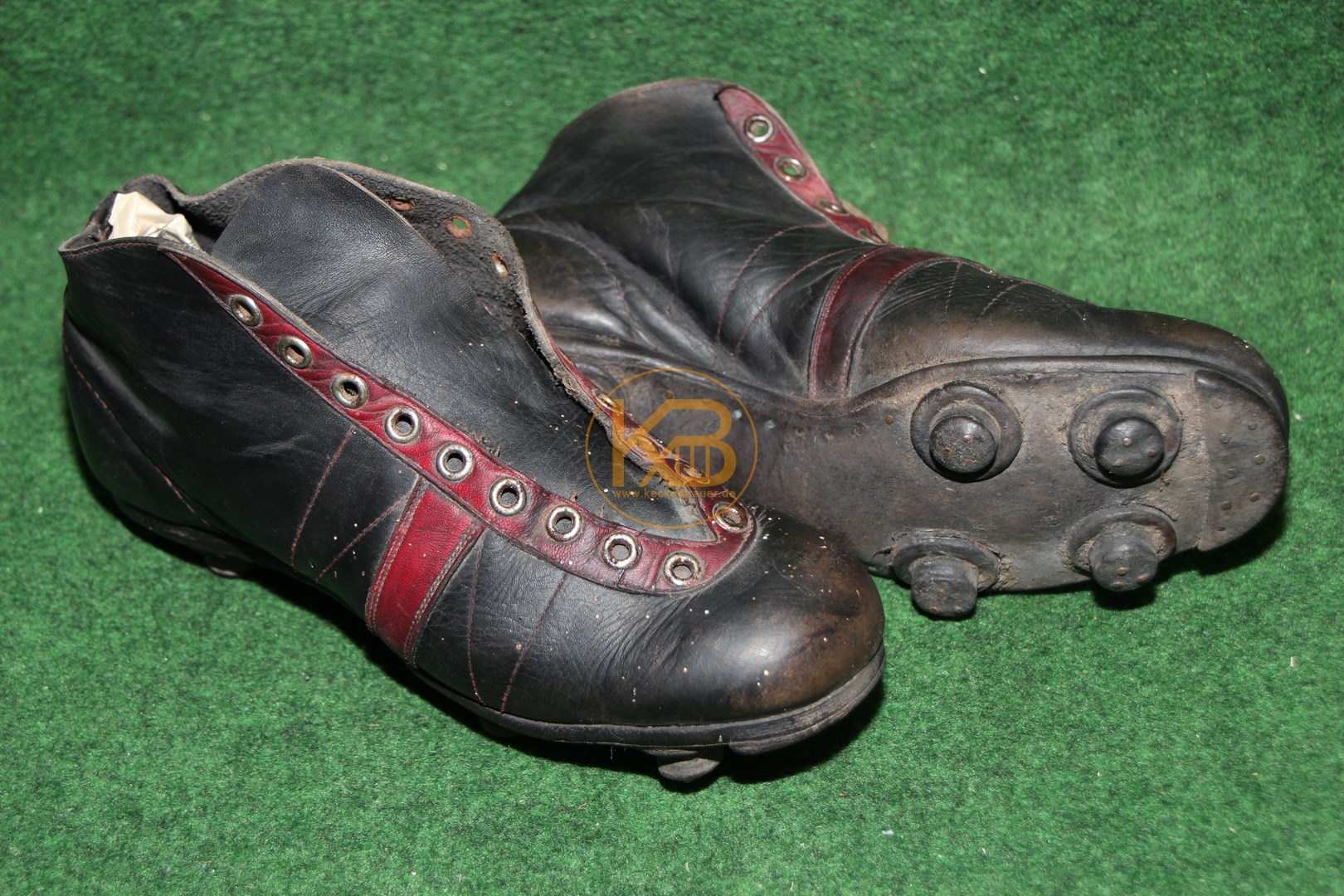 Schwarze hohe Fußballschuhe mit roten Applikationen mit genagelten Stollen aus den 1950er Jahren. In den Schuhen steckte eine Bildzeitung aus dem Jahr 1979. 1/2