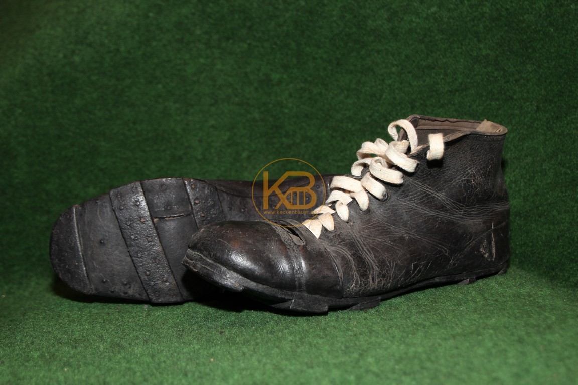 Hohe schwarze Fußballschuhe mit genagelten Lederriemen als Stollen.