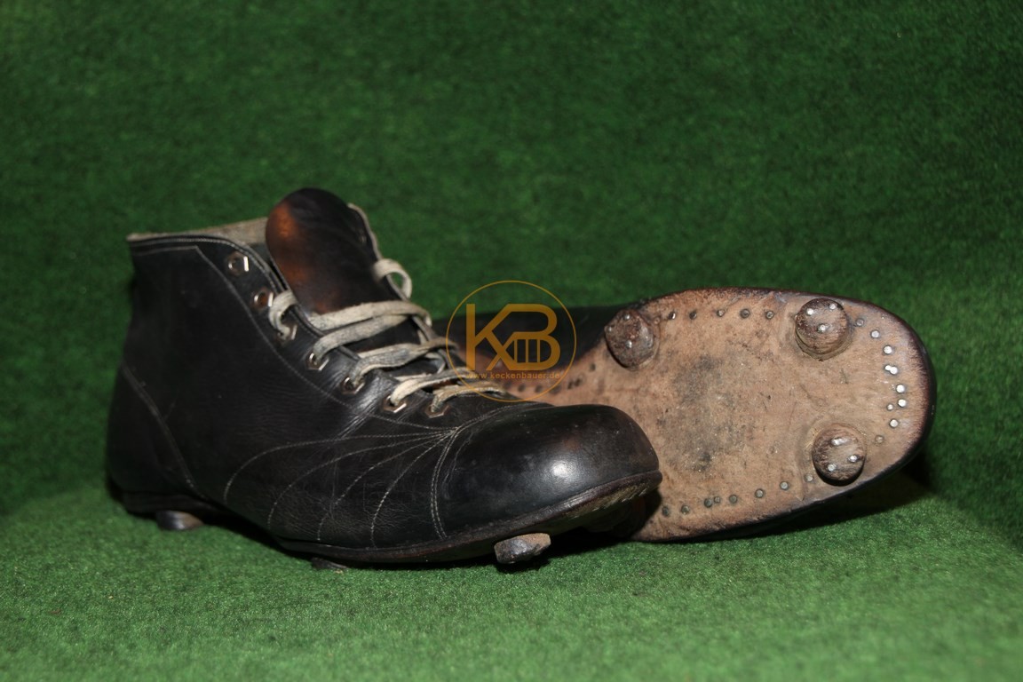 Hoher schwarzer Fußballschuh mit genagelten Rundstollen.