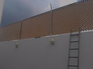Malla ciclónica galvanizada, con cinta plástica, colocada sobre barda.