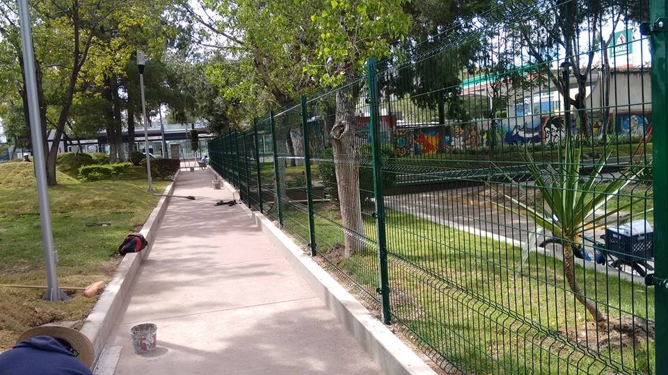 Reja de acero de 2 metros de alto. Postes y abrazaderás metálicas; todo en color verde.