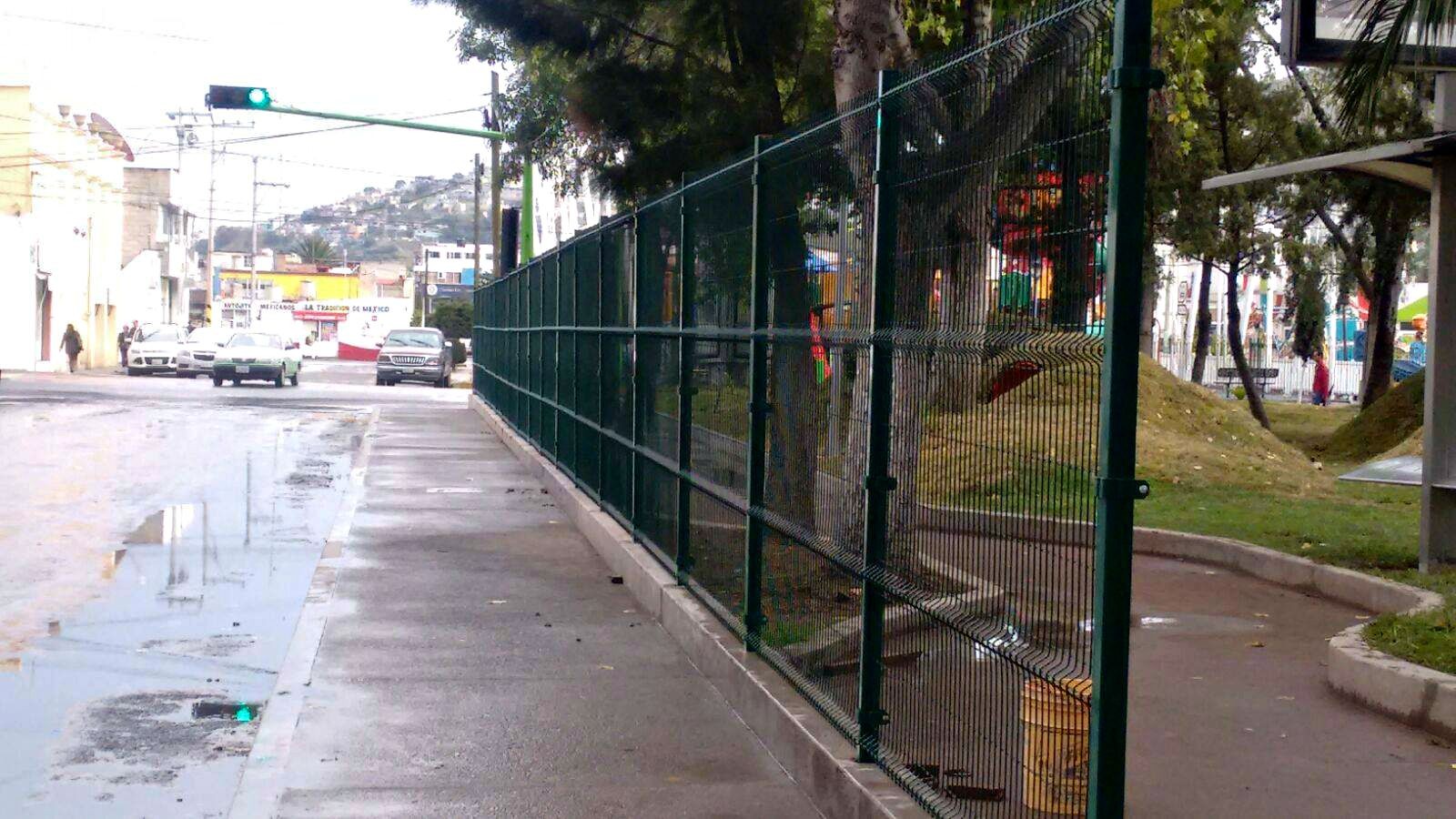 Reja de acero de 2 metros de alto. Postes y abrazaderás metálicas; todo en color verde.