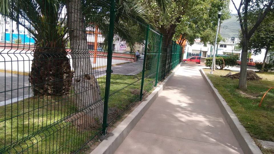 Reja de acero de 2 metros de alto. Postes y abrazaderás metálicas; todo en color verde.