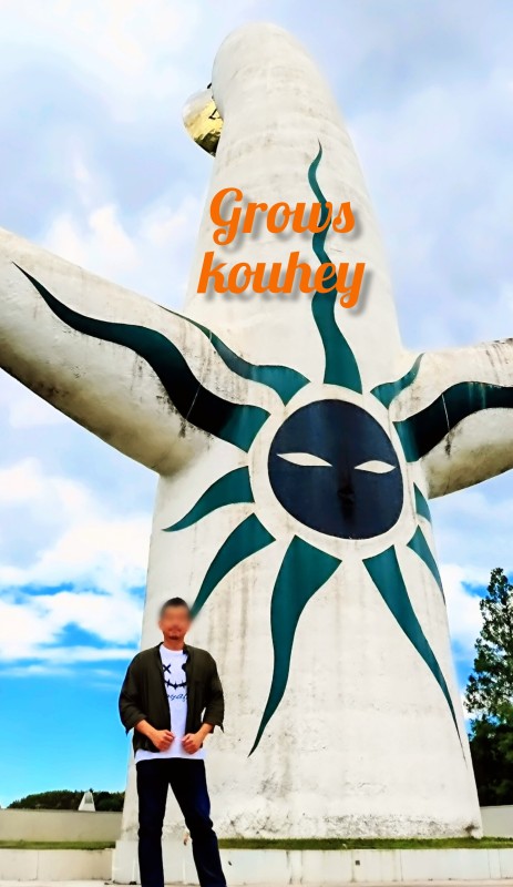 大阪のゲイマッサージGrows（グローズ）の男性セラピストKouhey（コウヘイ）。太陽の塔の前に佇むスタイリッシュな紹介画像。梅田・北区エリアのメンズトリートメント。