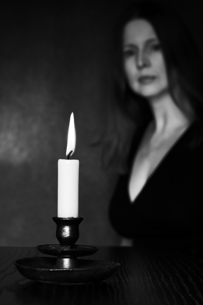 Manuela Deigert Projekte Selbstportrait mit brennender Kerze auf einem Tisch im Dämmerlicht
