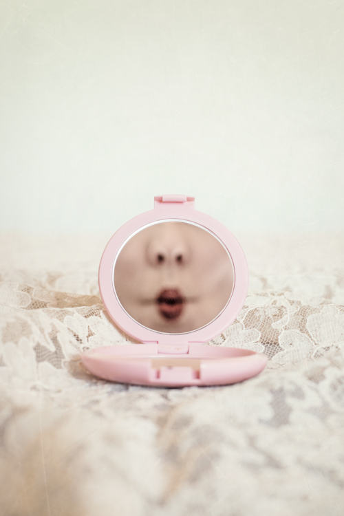 Manuela Deigert Bildsprache, Kussmund als Selbstportrait in einem kleinen rosa Handspiegel mit Spitzendecke als Untergrund
