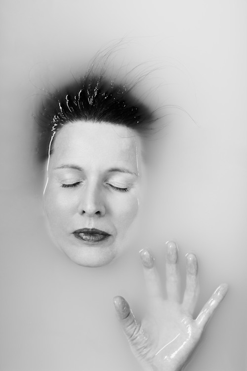 Manuela Deigert Bildsprache schwarzweißes Selbstportrait mit geschlossenen Augen und einer Hand in einer Badewanne 