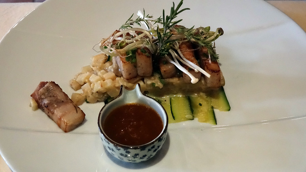 Poitrine de cochon de la ferme de la Beurrerie, rôtie, sur un lit de courgettes, risotto de céleri et aubergine, jus à la fleur de Macé des Indes
