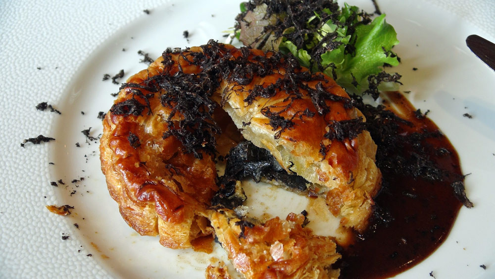 L'intérieur du Pithiviers de foie gras et truffes, sauce Périgueux, quelques pousses d’hiver en vinaigrette, râpée de truffes