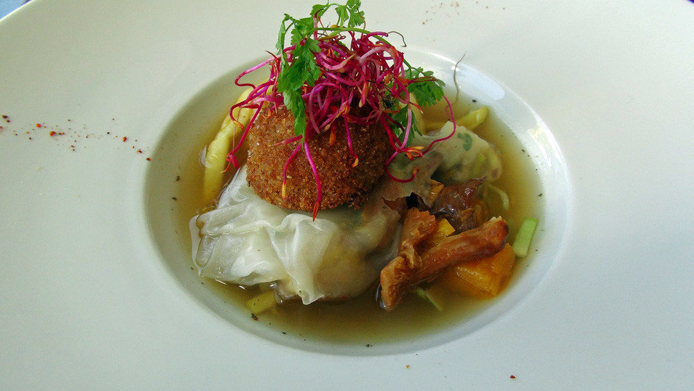 Consommé de légumes d'automne, raviole de giroles et châtaignes, jaune d'oeuf croquant