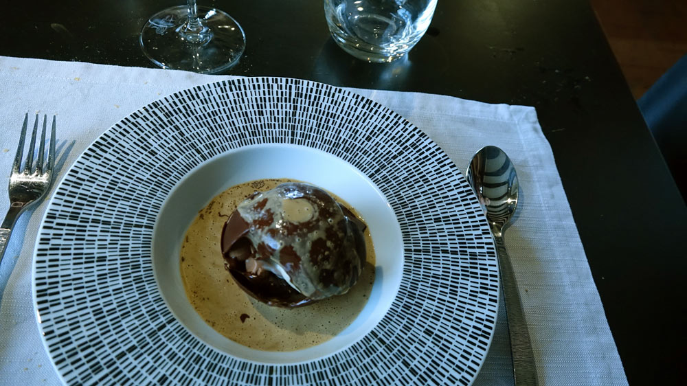 Coque en chocolat « Valrhona" fondue devant vous, crémeux chocolat grand cru, coque chocolat noir, glace fève de tonka, cappuccino de café, éclats de grué de cacao
