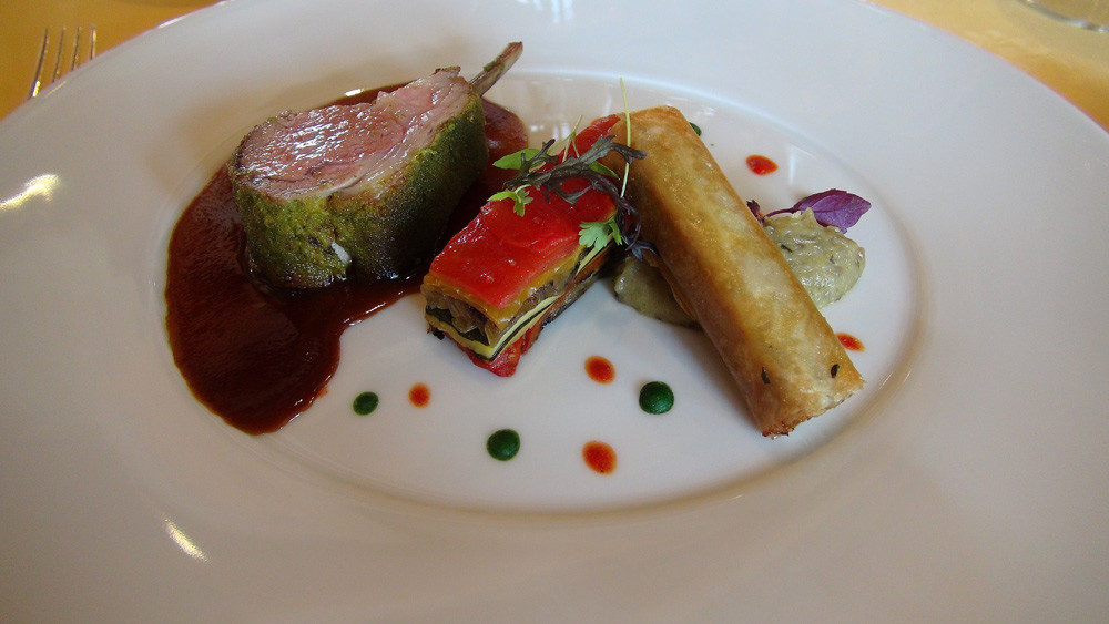 La côte double d'agneau : En croute d’herbes. Pressé de légumes grillés. Béarnaise d’aubergines.