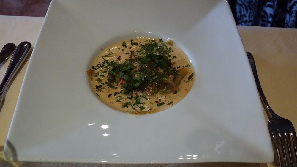 Ravioles de langoustines cuites à la vapeur, servies dans une bisque de homard parfumé au saté