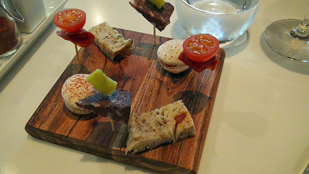 Amuse-bouche : Macaron "chorissero" - Pain focaccia à l'huile - Boudin froid maison et piment - Tomate cerise du jardin et chorizo
