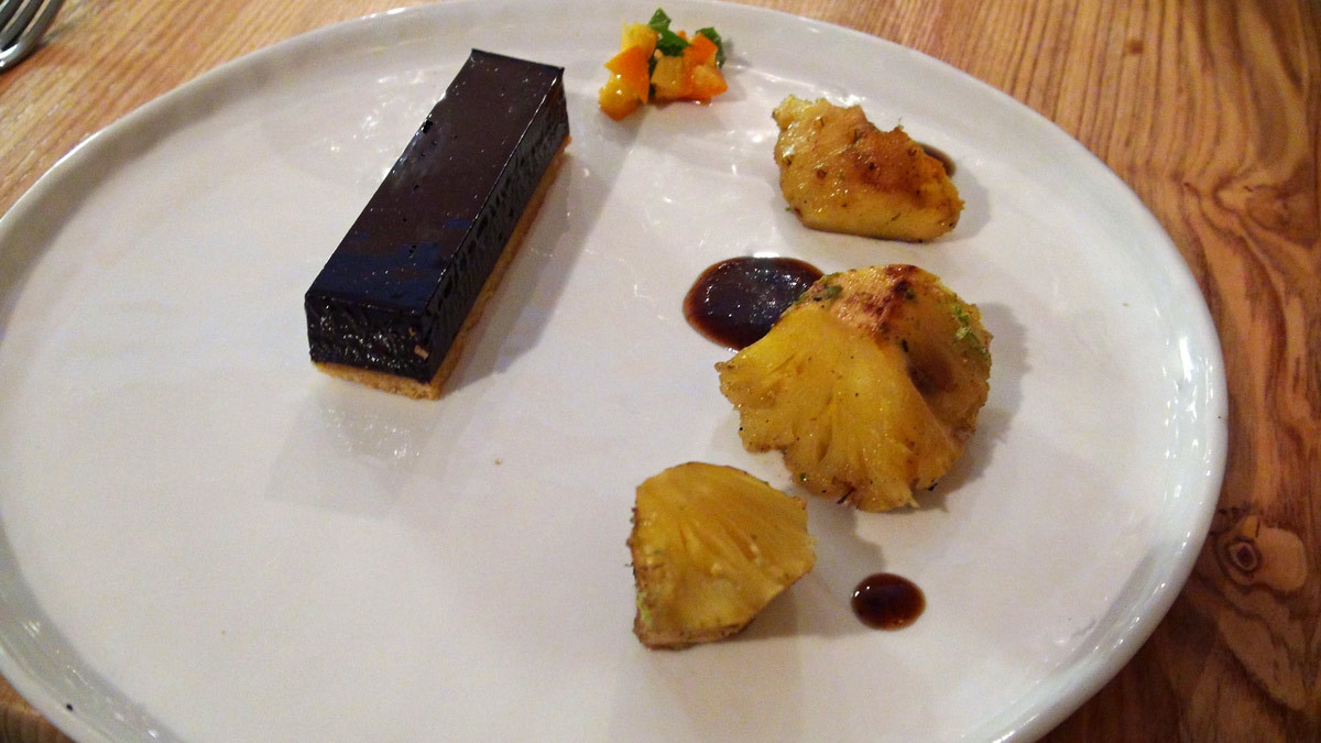 Ananas rôti aux épices, sauce aux pruneaux, tarte chocolat noir/tanaisie, kumquat et feuilles de menthe