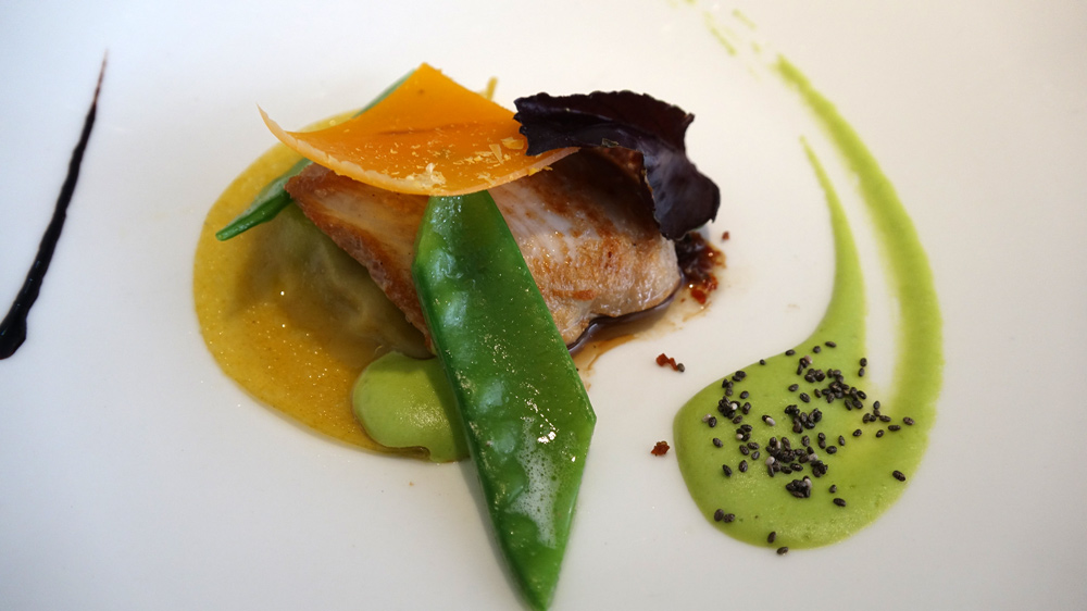 Raviole de lard fumé, caille, mimolette, crème de petits pois et poussière de jambon et laurier