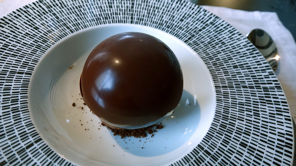 Coque en chocolat « Valrhona" fondue devant vous, crémeux chocolat grand cru, coque chocolat noir, glace fève de tonka, cappuccino de café, éclats de grué de cacao