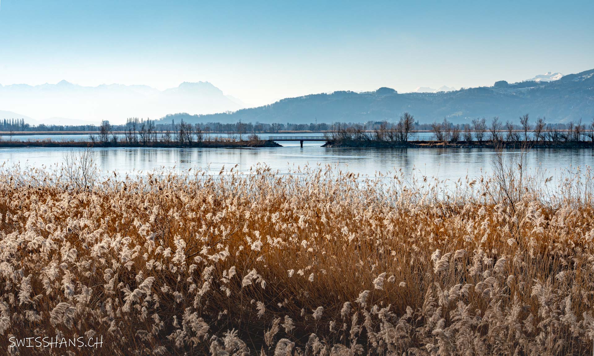 Winterlicher Lagunenrundweg mit Brücke im Rheindelta am Bodensee in Hard, Österreich.