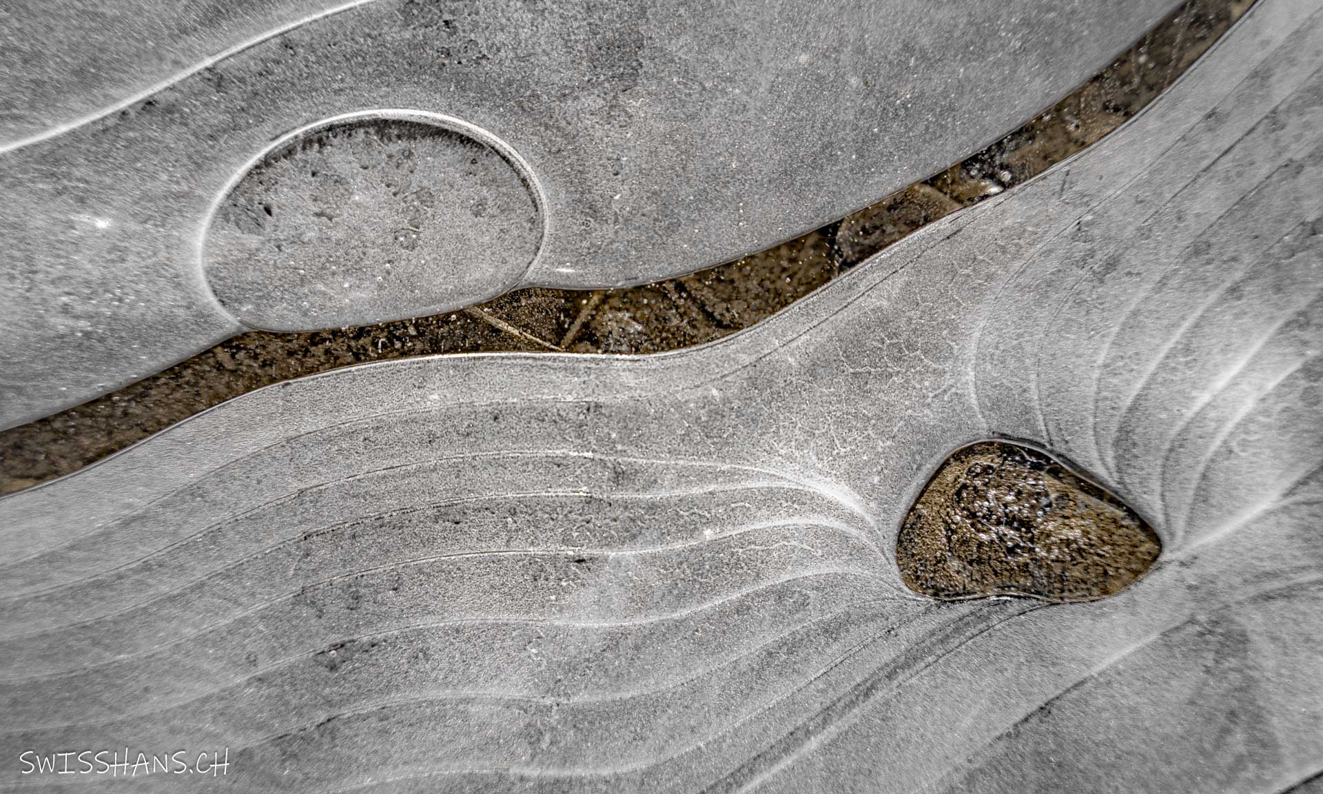 Einzigartig gemusterte Eisfläche mit geschwungenen Linien zum eingefrorenen Stein.
