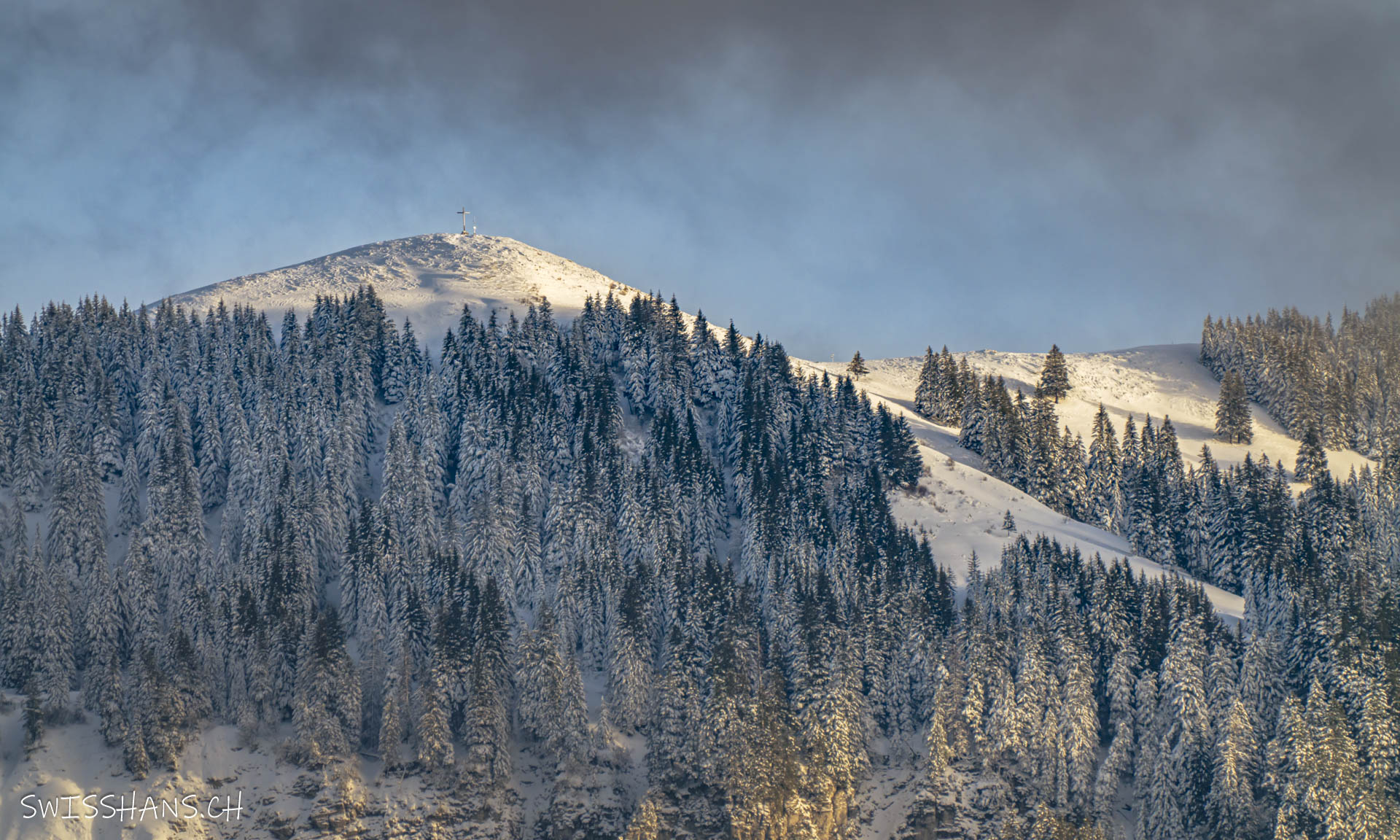 Blick zum Rheintaler Hausberg "Hohen Kugel" mit Gipfelkreuz und Winterlandschaft.