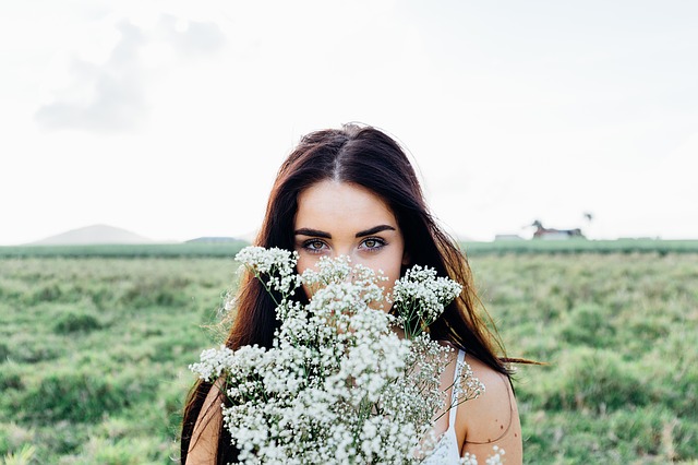 Junge Frau auf einer Wiese hält einen Blumenstrauß