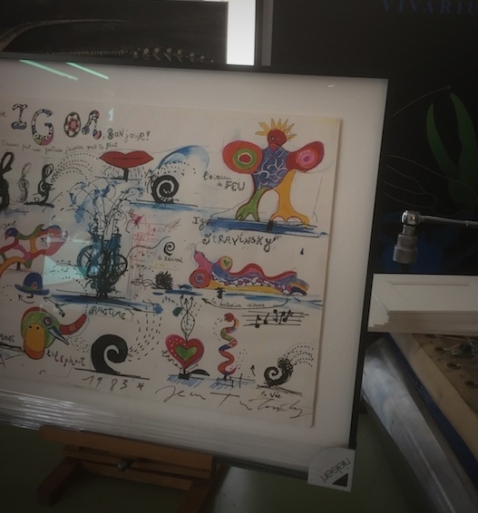Plakat von Jean Tinguely mit Widmung, erhöht aufgelegt auf hellem Museumskarton mit Schattenwurf