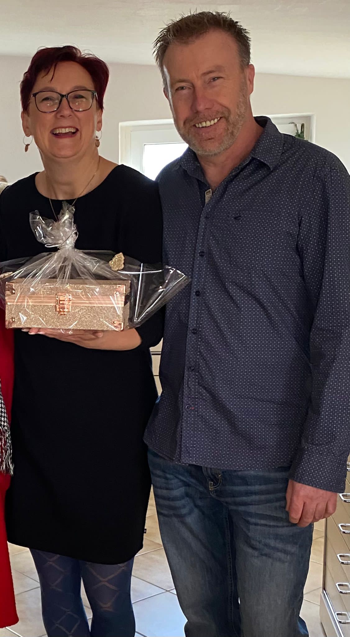 Maren und Thomas schauen in die Kamera mit einem Geschenk in der Hand.