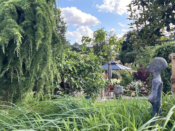 Skulptur aus Steinzeugmasse, im Hintergrund Gartenanlage mit Pavillon der SommerGalerie