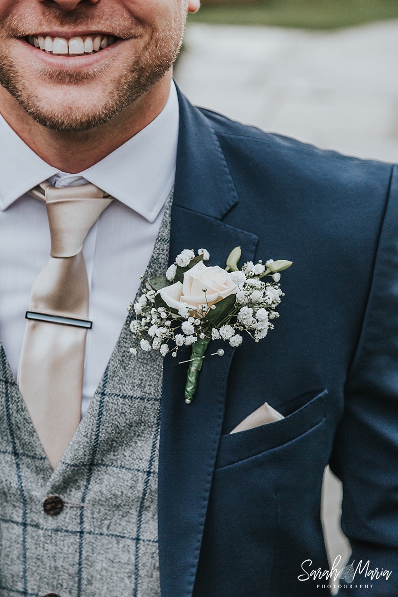Grooms boutonniere featuring a rose and gypsophila
