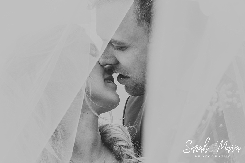 bride and groom portrait looking through a veil in black and white