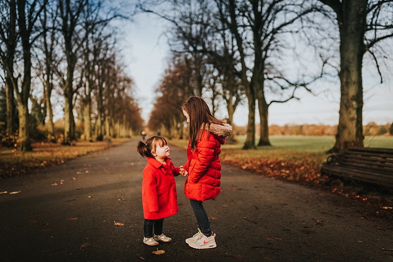 sisters in red coats at the park in Preston